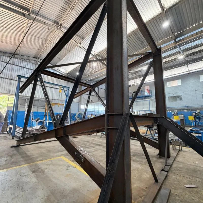 Estrutura metálica treliçada em fabricação dentro do galpão